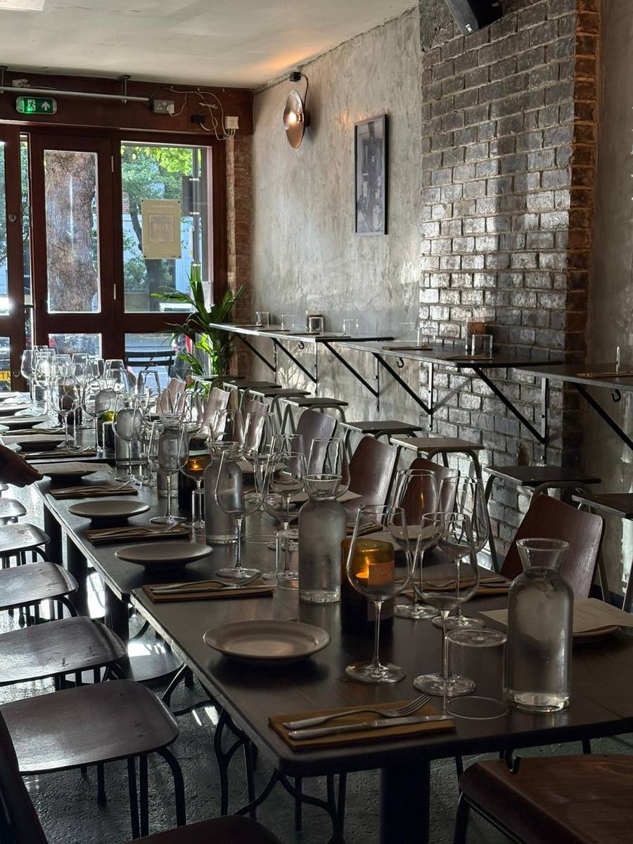 The finished dining room at Table at 464 - long table laid with wine glasses, exposed brick and plaster walls